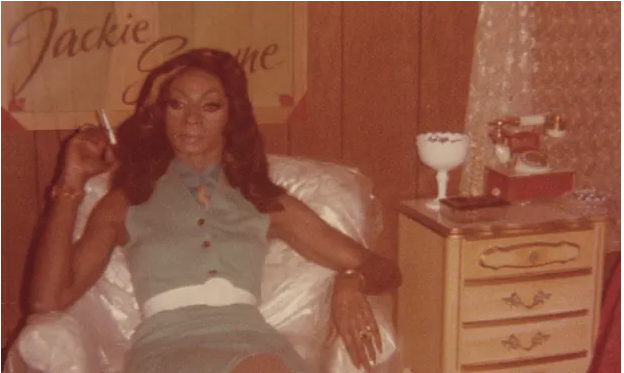 Faded color photo of Jackie Shane lounging on a bed with a cigarette in her hand