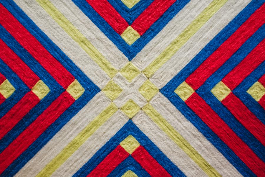 Stitchwork in green, white, red, and blue resembling an X. 
