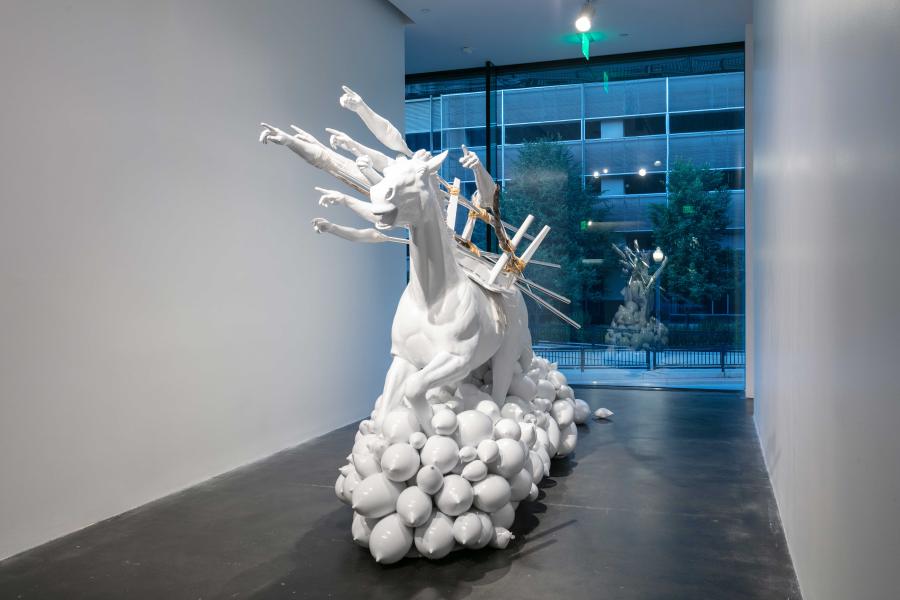 Large white fiberglass horse in an MCA Denver gallery. Plaster casts of arms affixed to the horse are pointed upward, creating a sense of momentum.