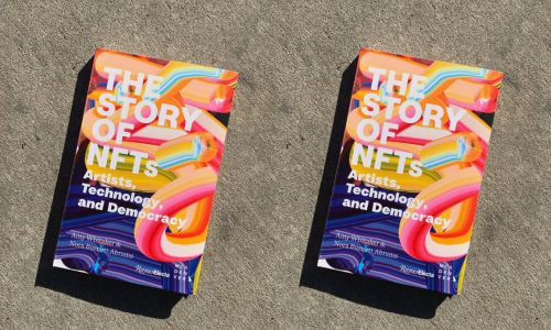  Book photographed on concrete in bright sunlight. The title of the book, printed in white font, reads “The Story of NFTs”. The cover of the book is colorful and looks like layered brush strokes. 