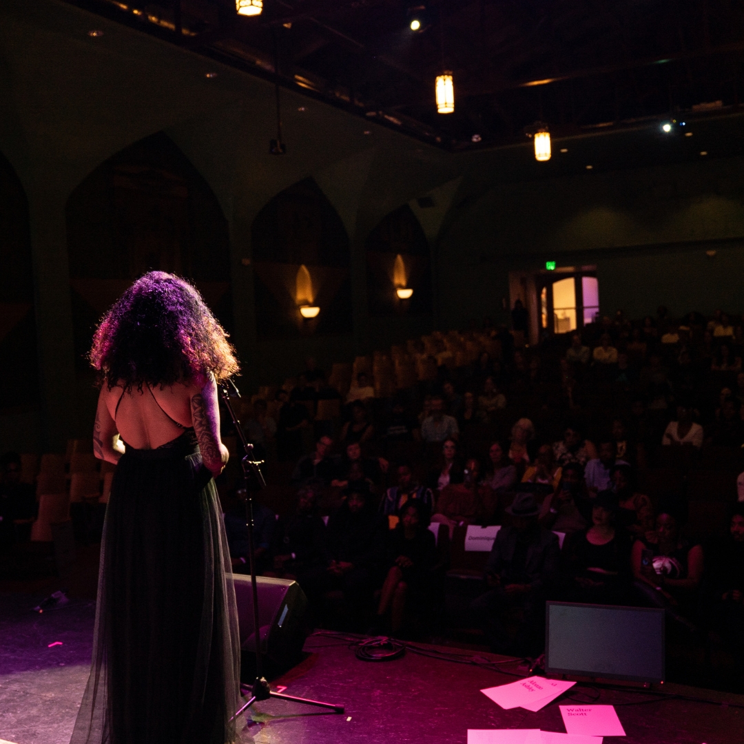 Performer on a stage with their back facing the camera.