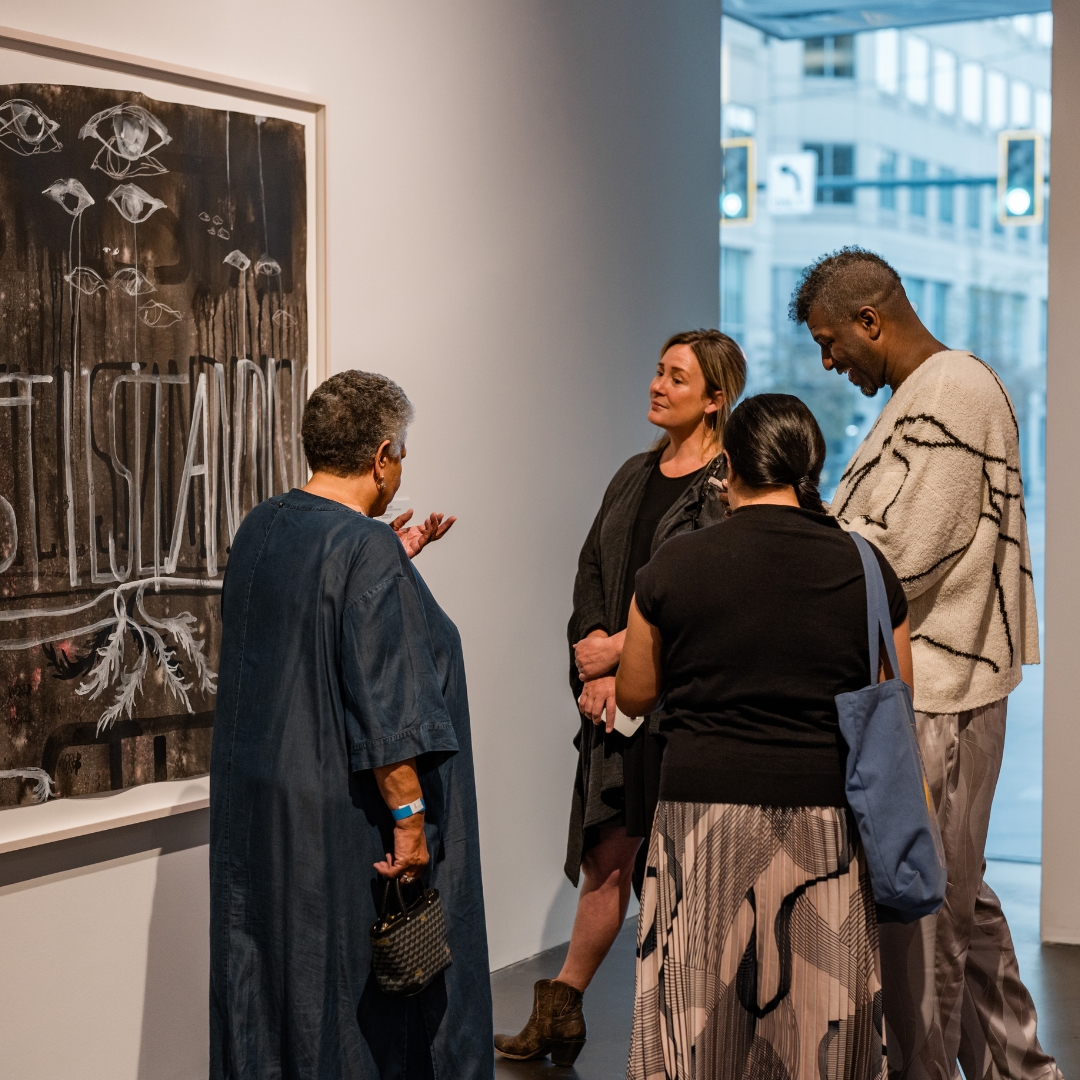 Four people standing and mingling in a gallery.