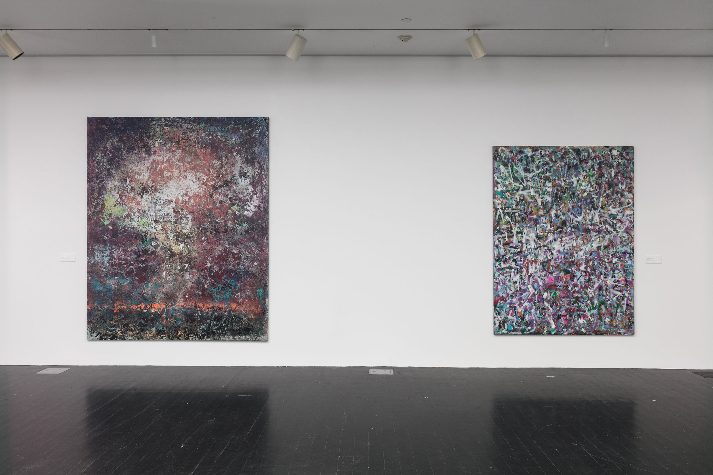 Two large abstract paintings hang on a white gallery wall. 
