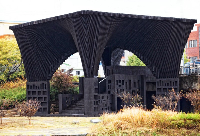 Photo of Gwangju River Reading Room in the outdoors during the day. It is a large dark structure resembling a voxelated desk.