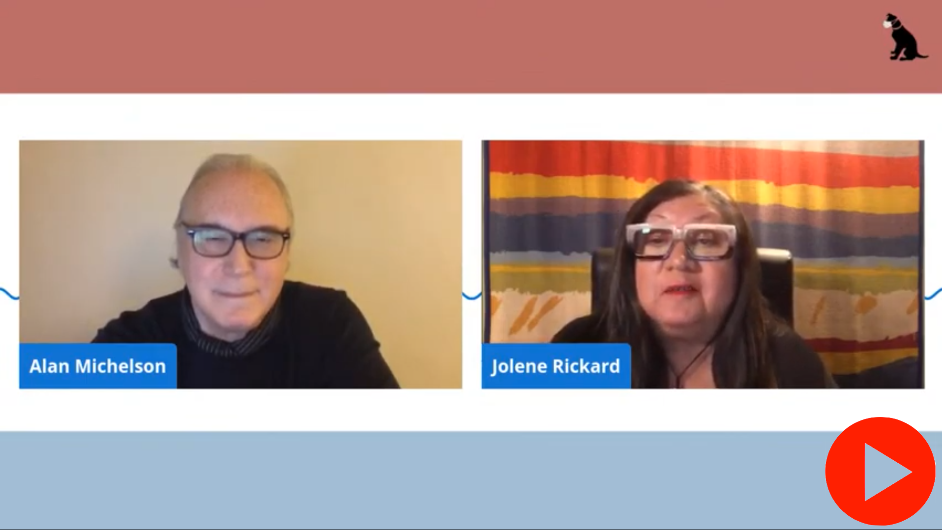Image of Mohawk member of the Six Nations of the Grand River artist Alan Michelson on Zoom next to Indigenous scholar, Jolene Rickard, who wears dark rimmed glasses, a black sweater. He has gray hair and sits against a blank beige background. Jolene sits against a bright colorful backdrop and she wears dark rimmed glasses and has dark shoulder length hair. There is a red play button on the bottom right corner of the image.
