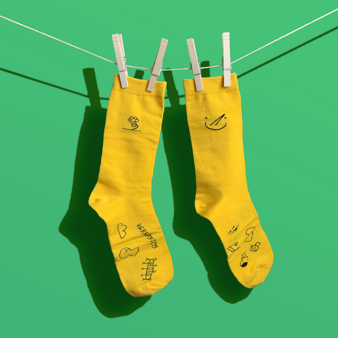Yellow socks hung in front of a green background.