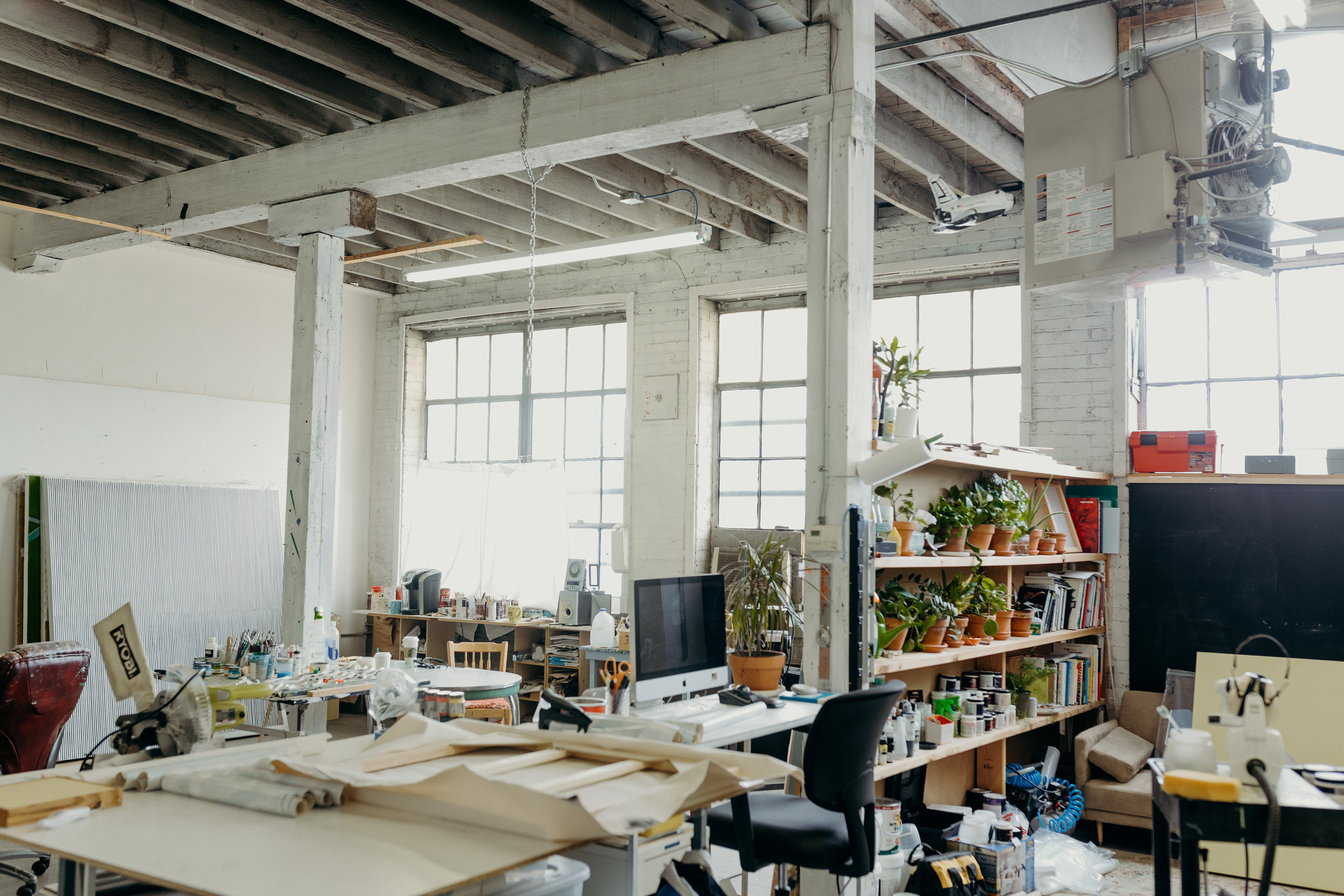 An indoor work space with high ceilings and tall windows. ﻿