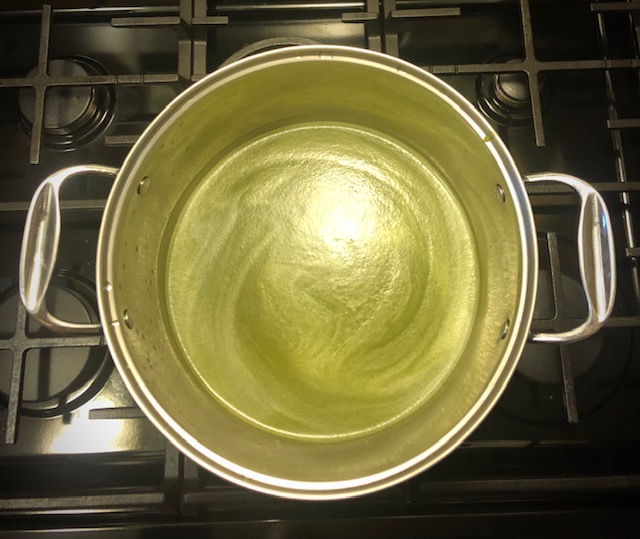 Aerial view of a golden green soup in a stainless steel stock pot. 