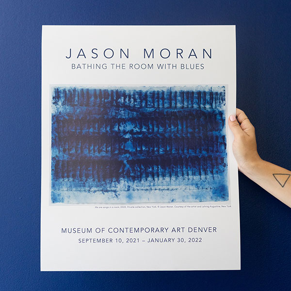 [Image description: Photo of a hand holding up the official Jason Moran MCA Denver poster.]