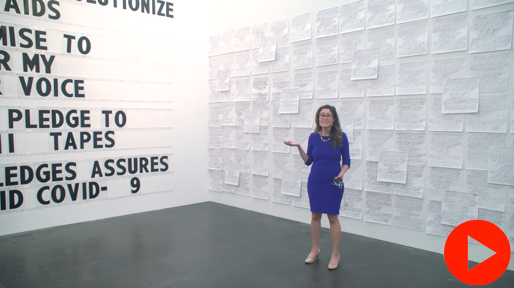 Screenshot of MCA Denver Ellen Bruss Senior Curator, Miranda Lash, standing in front of Paul Ramirez Jonas’ work. Behind her is a wall covered in dozens of pieces of paper with indistinguishable text.