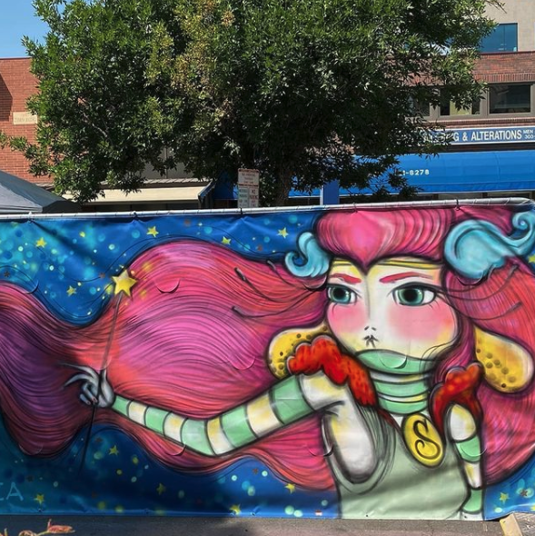 Photo of a colorful artwork from the artist on an outdoor wall. 