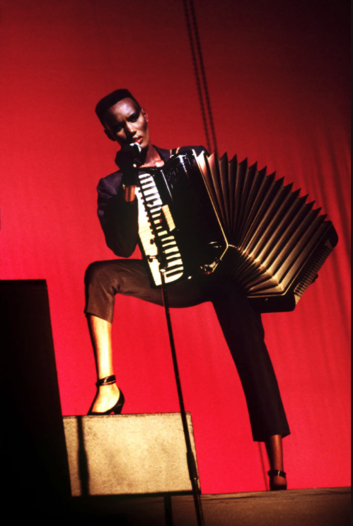 photo of Grace Jones, red background with an accordion 