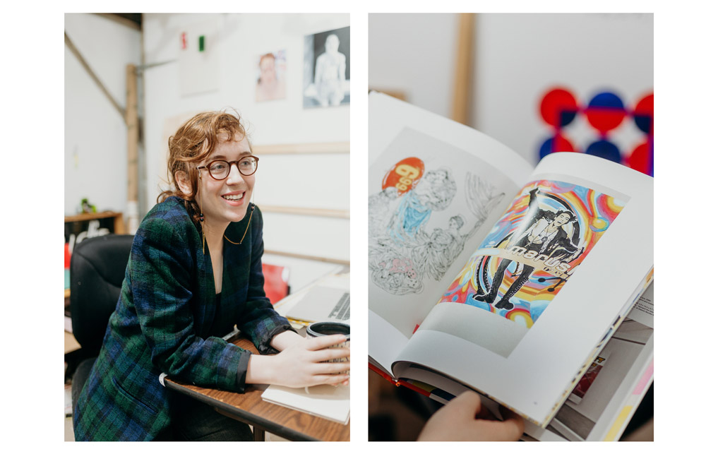 Sierra sitting at a desk with a mug in her hands. She is smiling. A book is open to a page depicting a man with a colorful, hippie like background.
