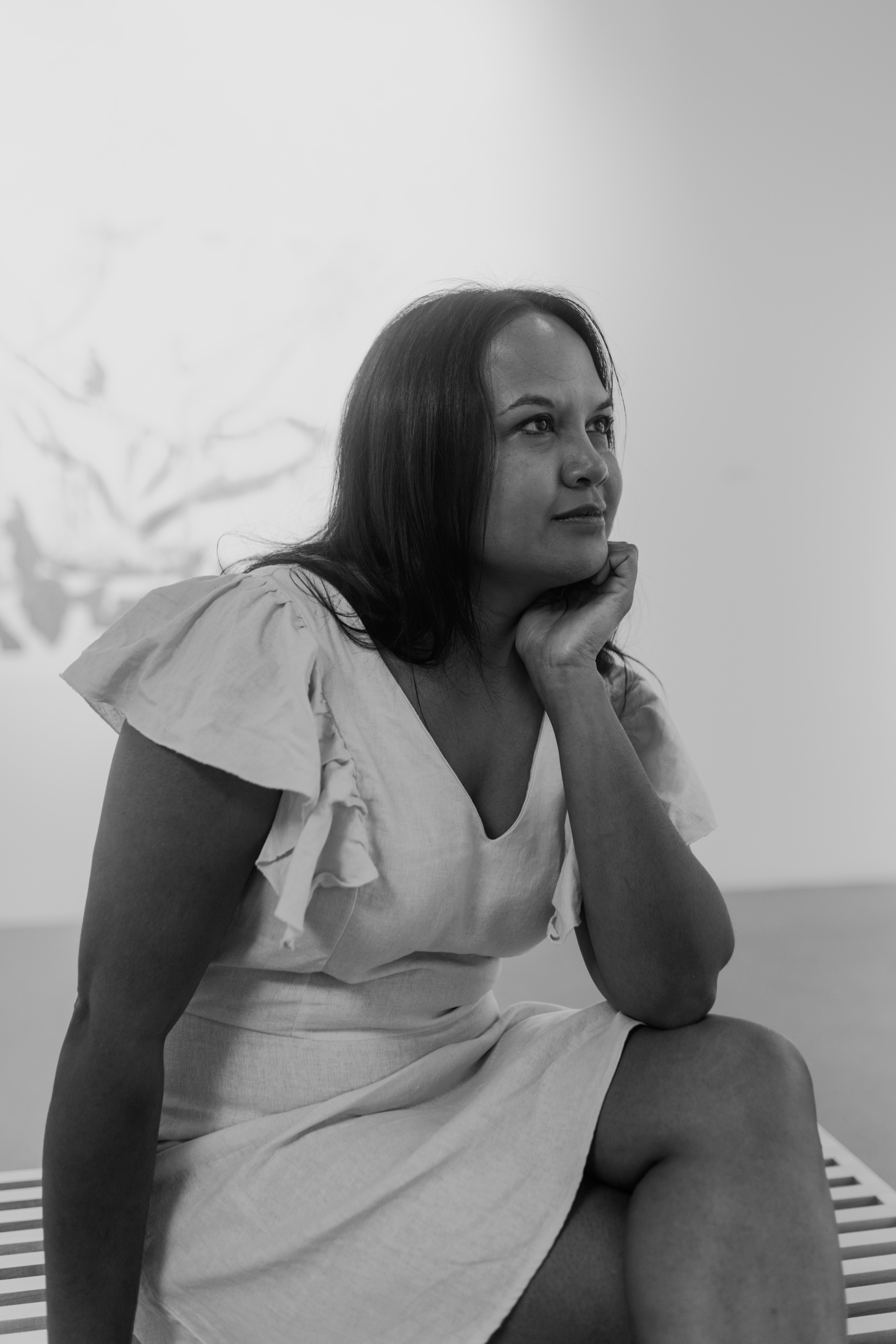 Black and white portrait of suchitra sitting with her chin in her left hand. It appears as if she is mid-thought. 