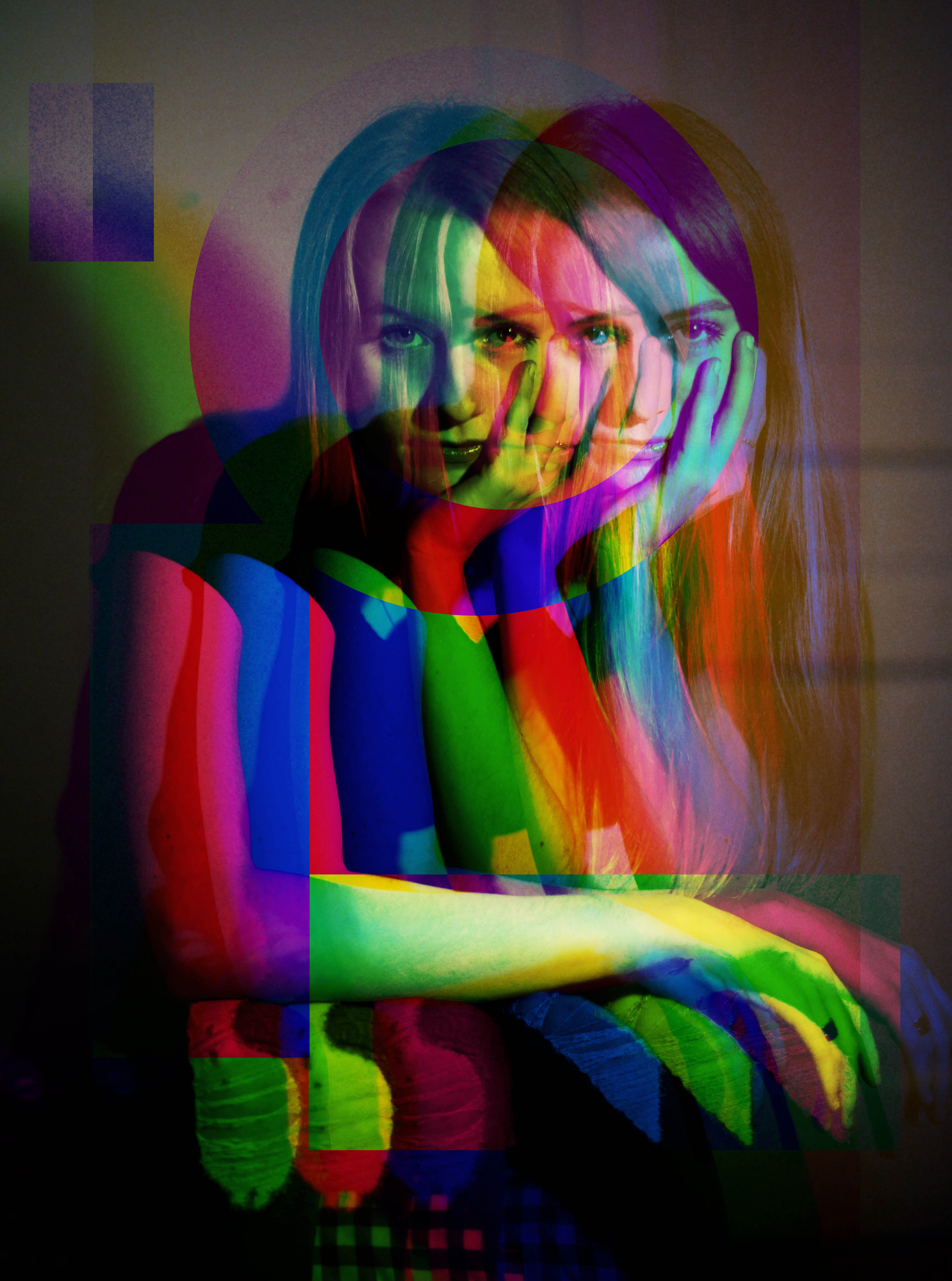 A portrait of a woman seating and staring into the camera. She is duplicated and superimposed over herself in different transparent colors. 