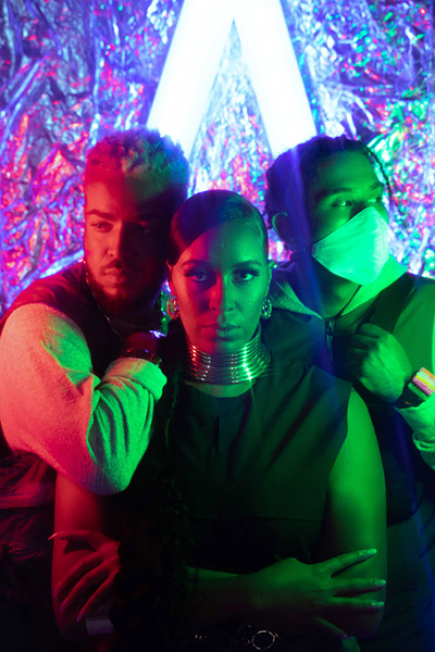 photo of the band. Color gel lights in the back giving neon colors of pink, blue and green