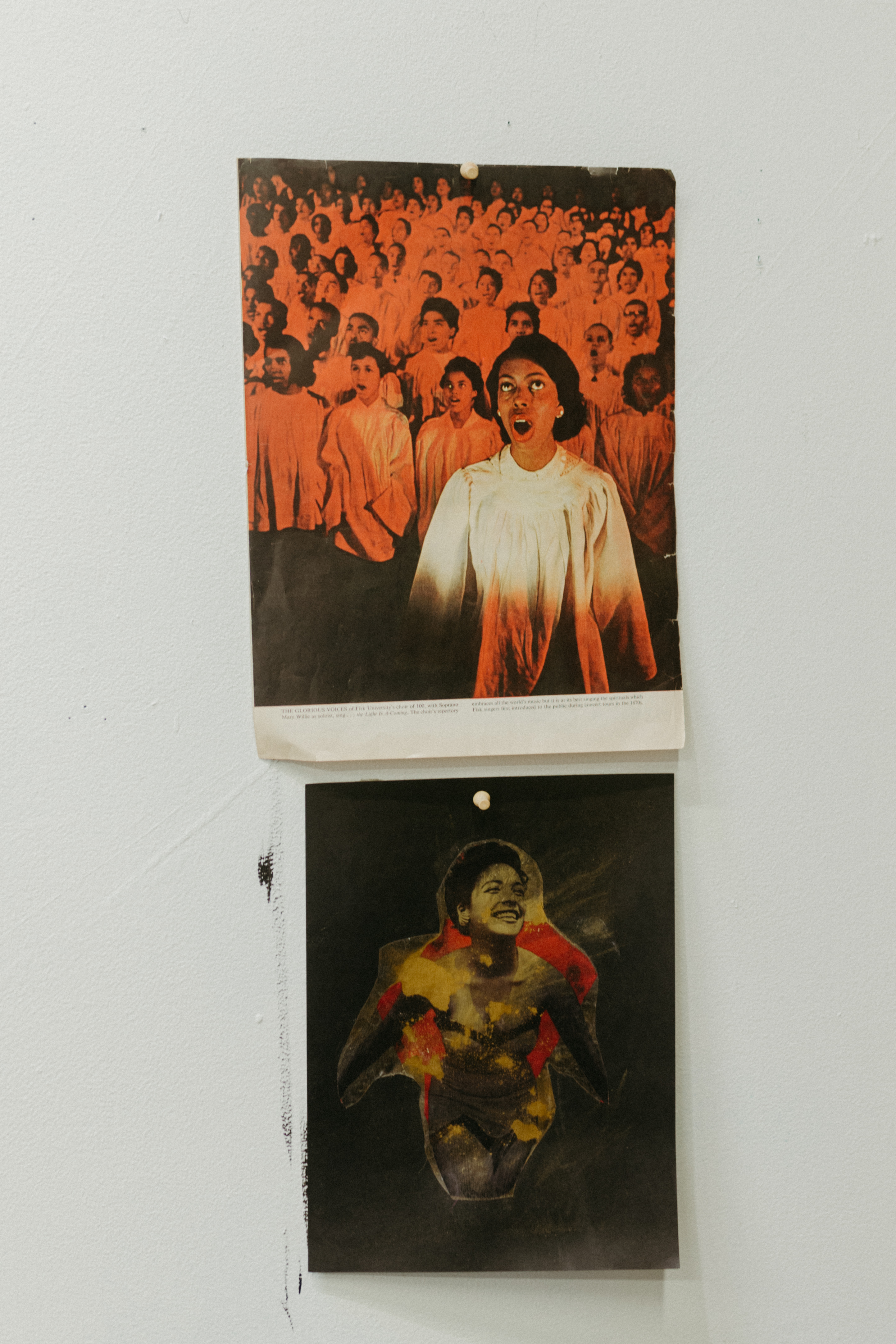 Photographs on the wall of Anthony's studio. One is of several people in a choir, a woman is front and center wearing a white dress singing. The other image is of a smiling woman. 