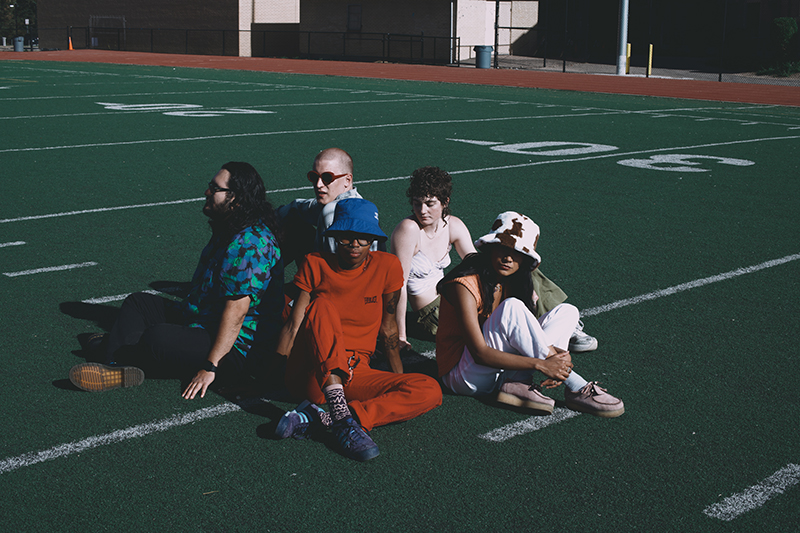 Band shot of the band, Waiting Room. Sitting perfectly arranged in the middle of a football field