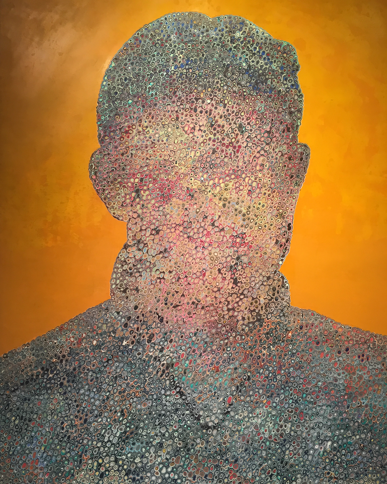 A painting of a person. The background is a warm yellow. The subject’s silhouette is made up of hundreds of drilled holes revealing the several colored layers of paint. 