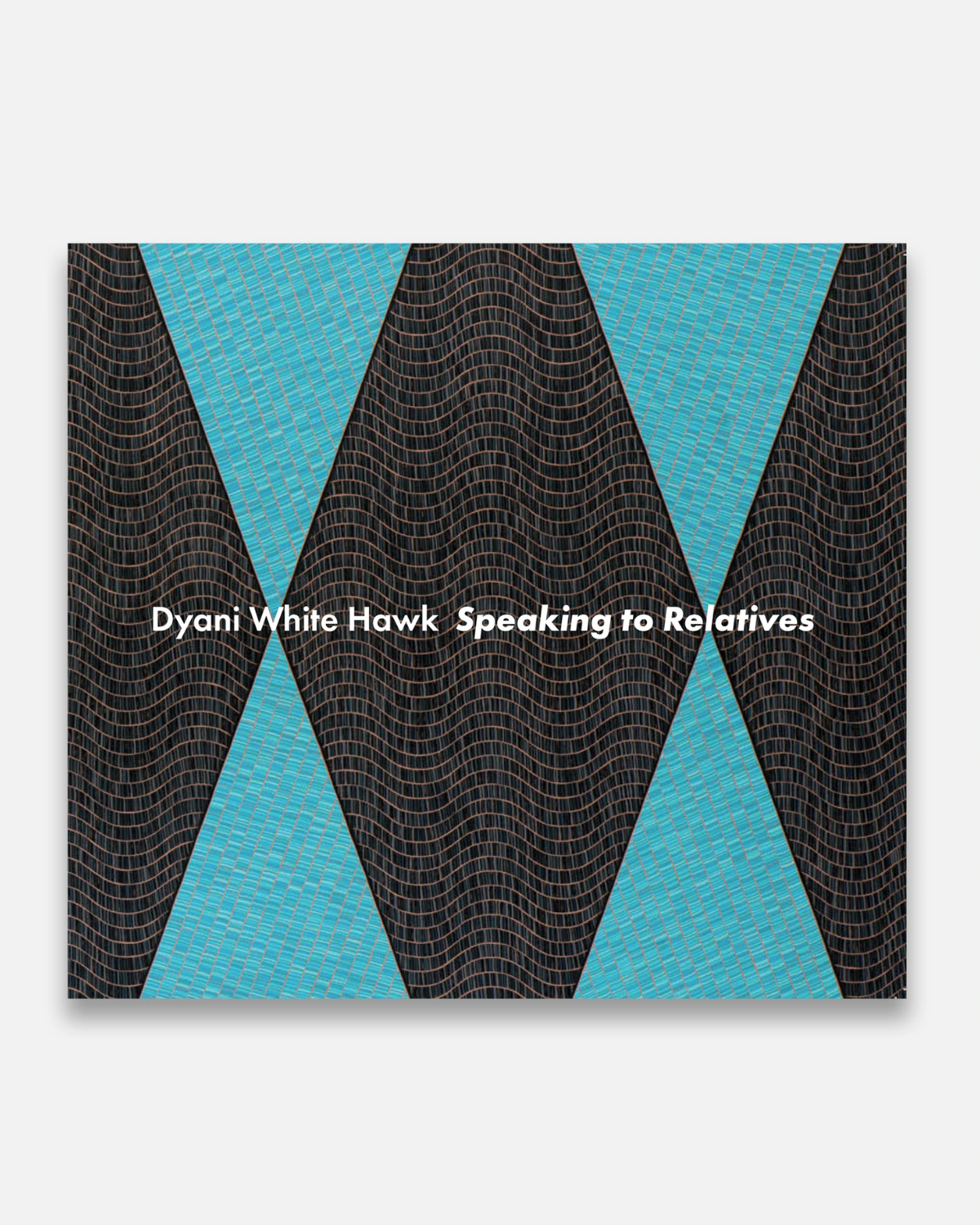 Exhibition catalogue photographed on a white background. White text on the center of the catalogue reads, “Dyani White Hawk Speaking to Relatives.” The catalogue cover art is made up of large triangles in blue and large diamond-like shapes in a brownish color.