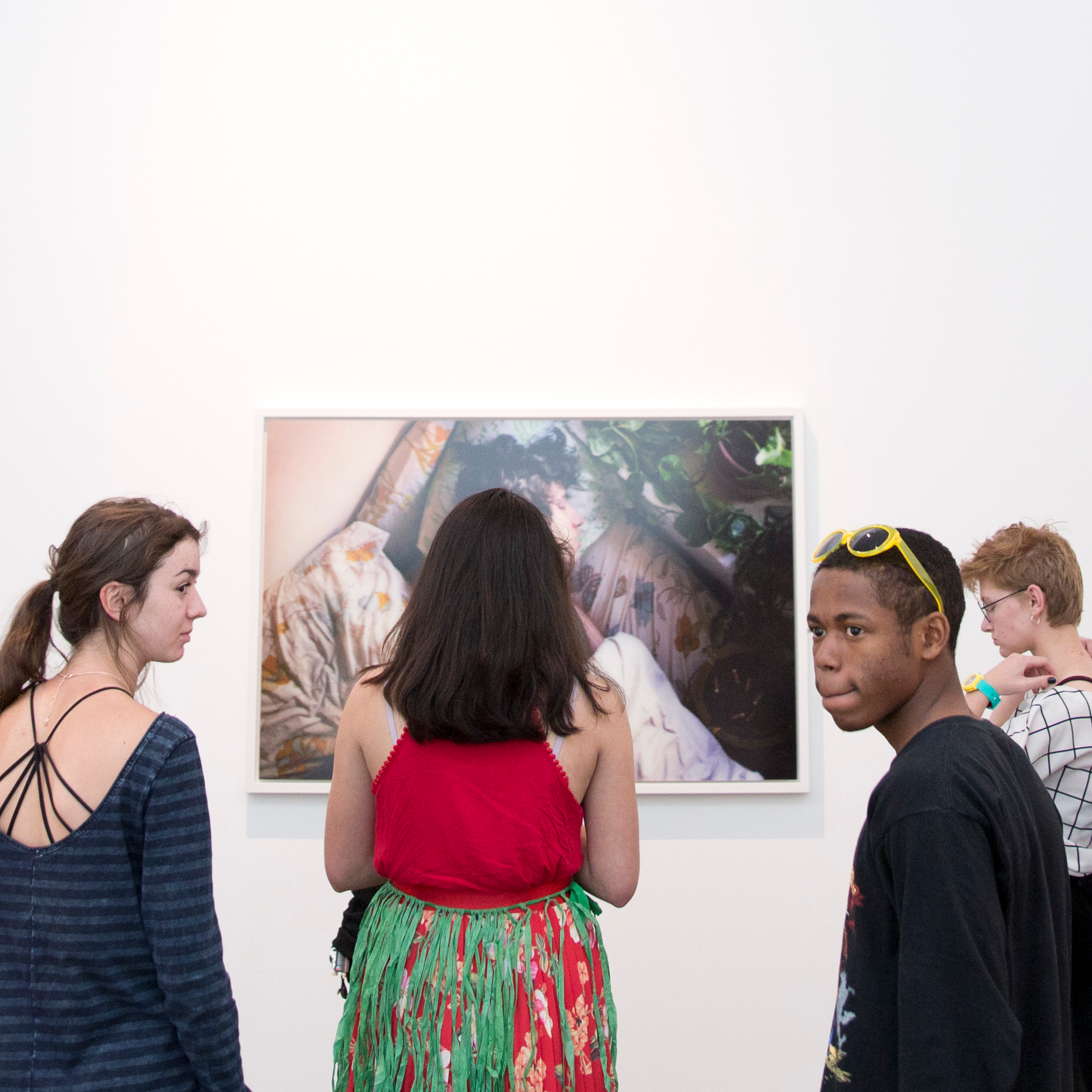 Four visitors looking at a photograph hung on a white gallery wall.
