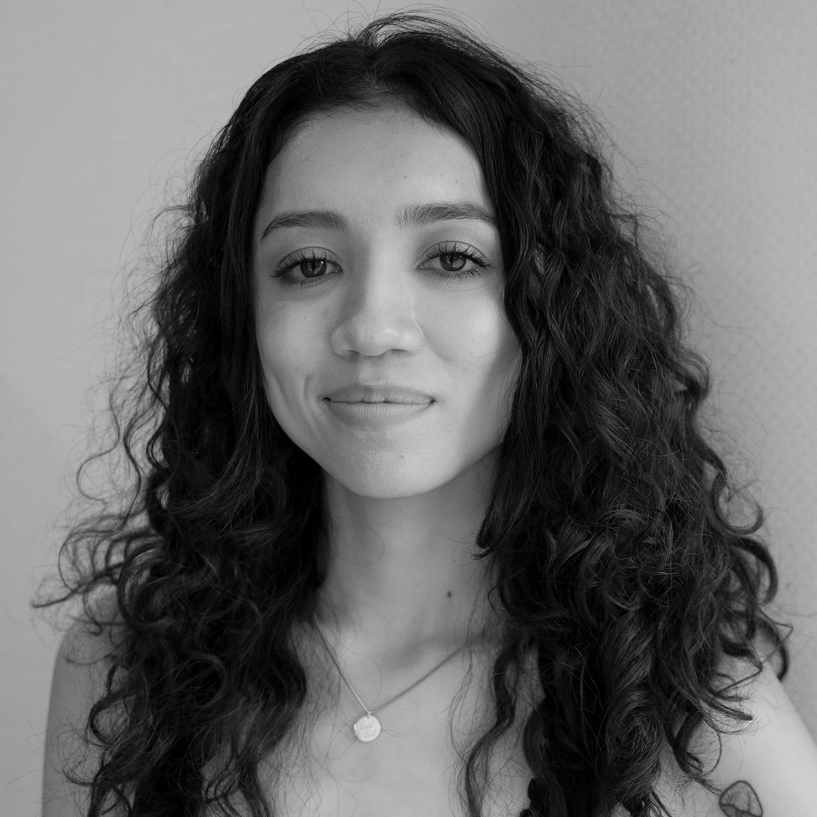 Black and white portrait of Mia Foster, sporting a soft smile and curly hair.