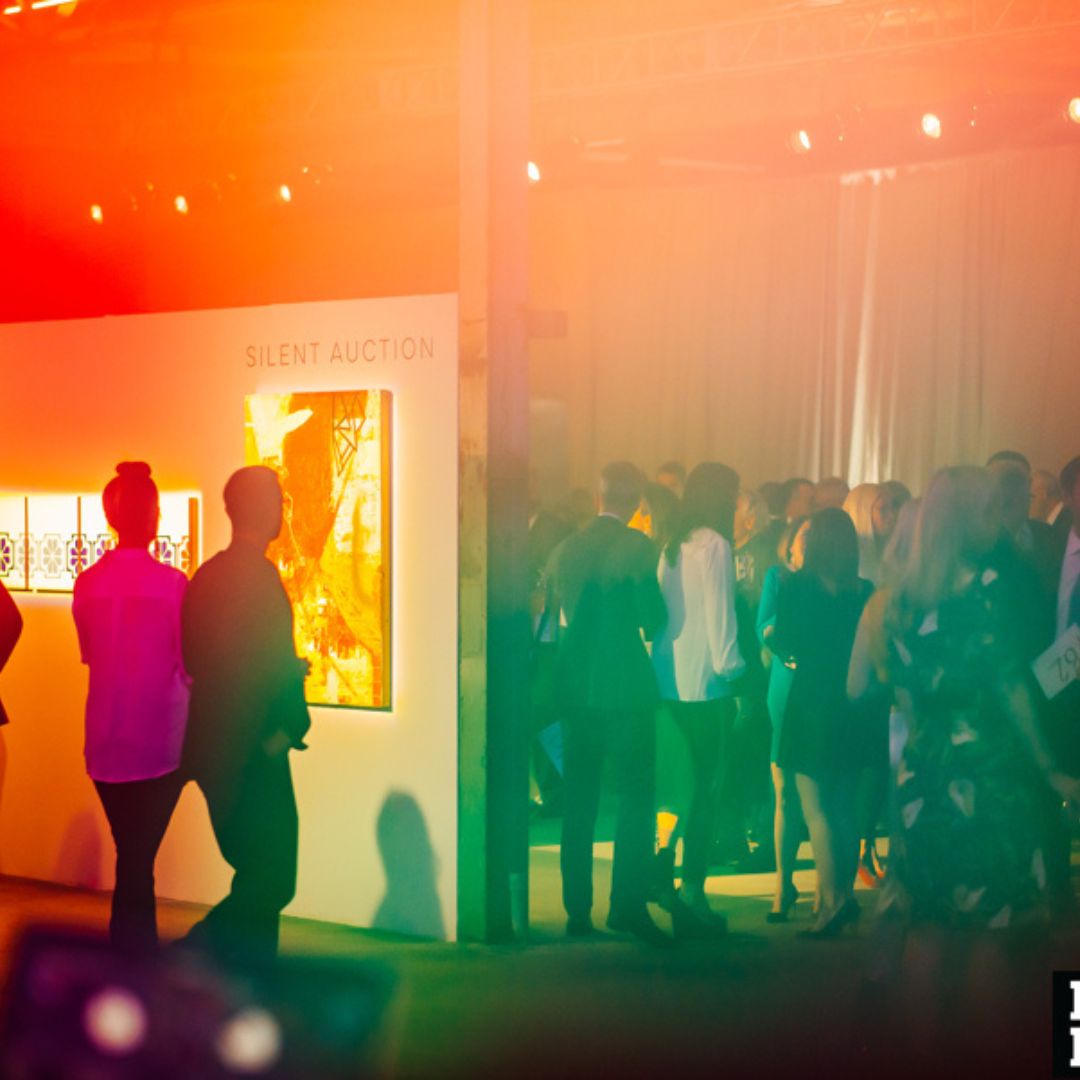 People at a gala. Some are mingling, some are looking at art.