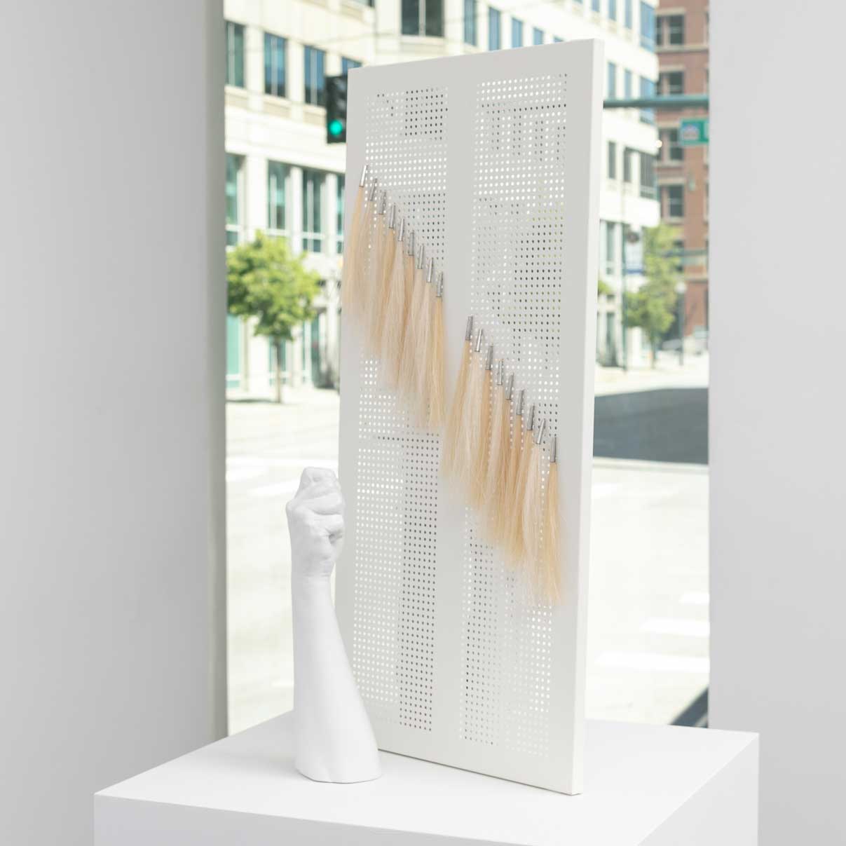White sculpture on a plinth, photographed in front of a window.
