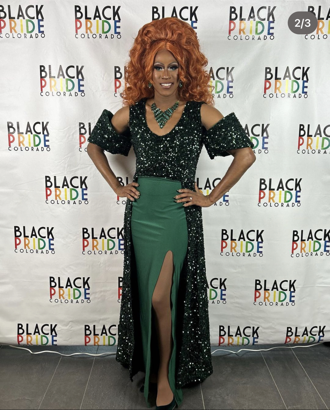 Juiccy Misdemeanor in front of a step and repeat background for Black Pride Colorado