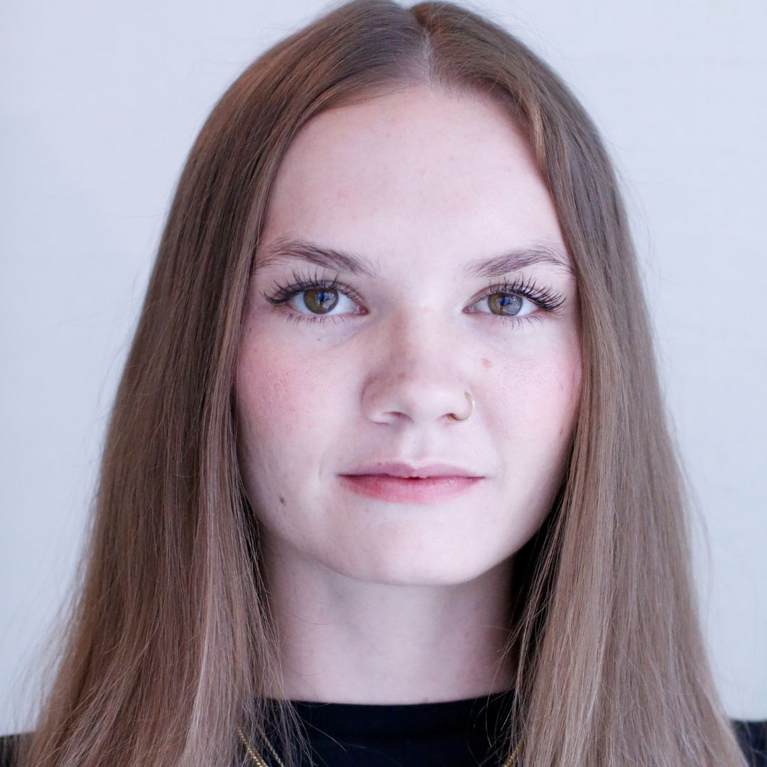 Close up portrait of a person named Chandler Norval. She is sporting straight hair and a serious look on her face, while standing in front of a white background.