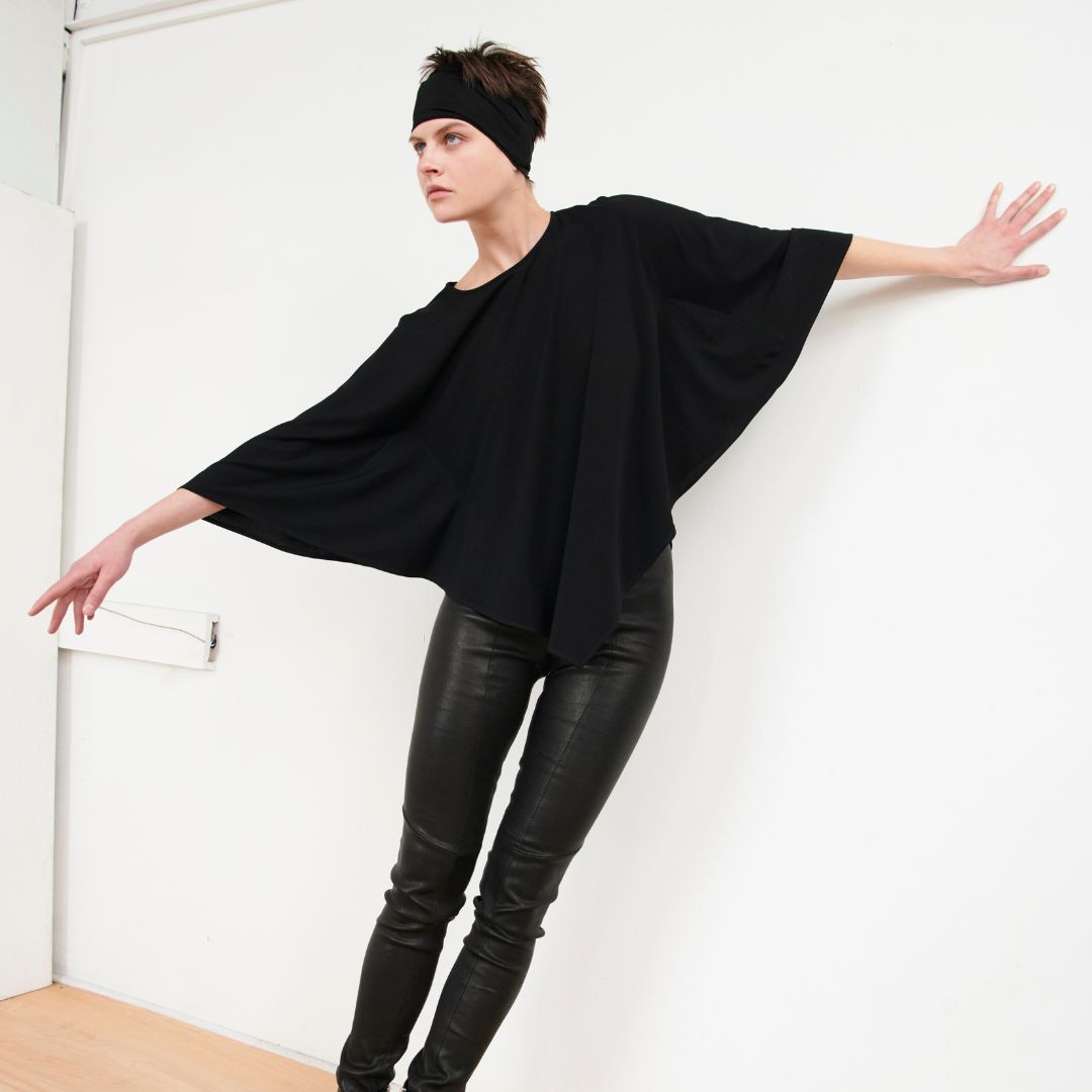 Model wearing a black outfit while leaning up against the wall.