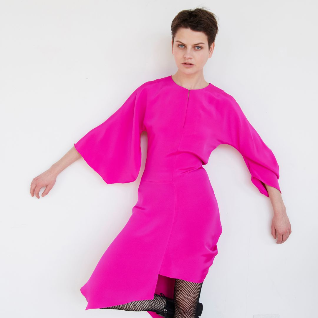 Modeling wearing a bright pink dress.