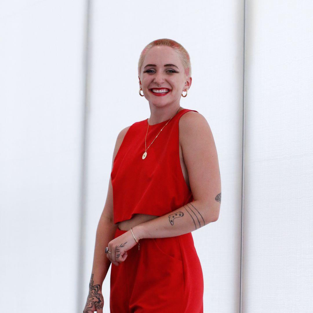 Person named Parker Kaufmann wearing a matching red top and pants, smiling big in front of a bright white background.