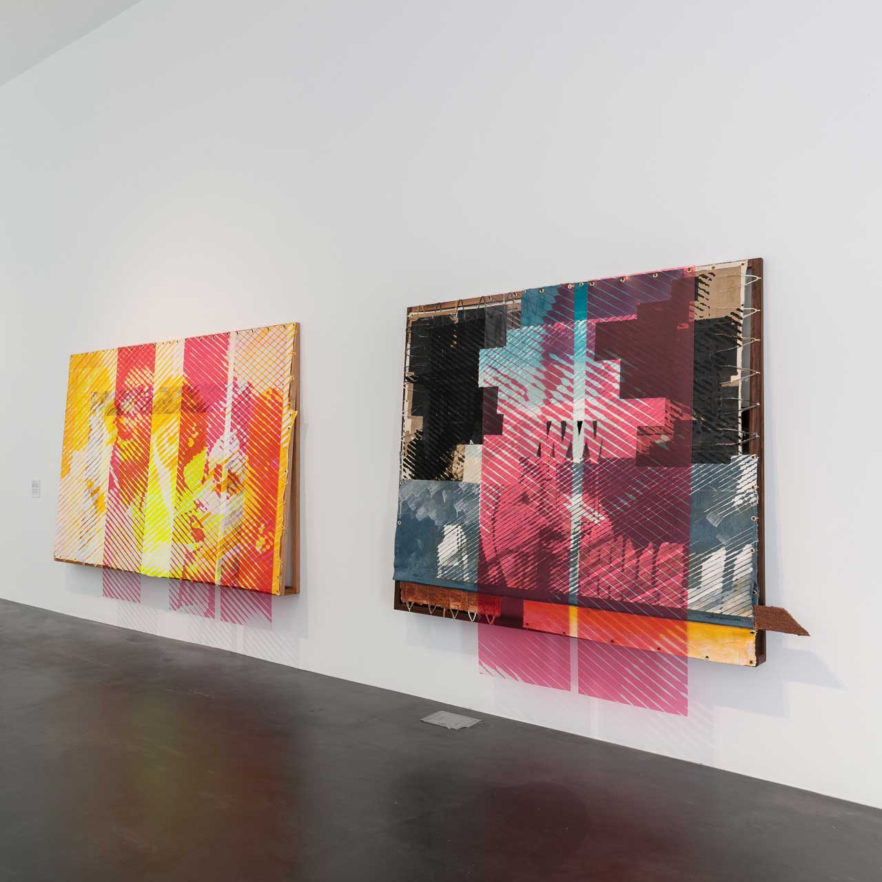 Two large, colorful abstract artworks hung on a white gallery wall.