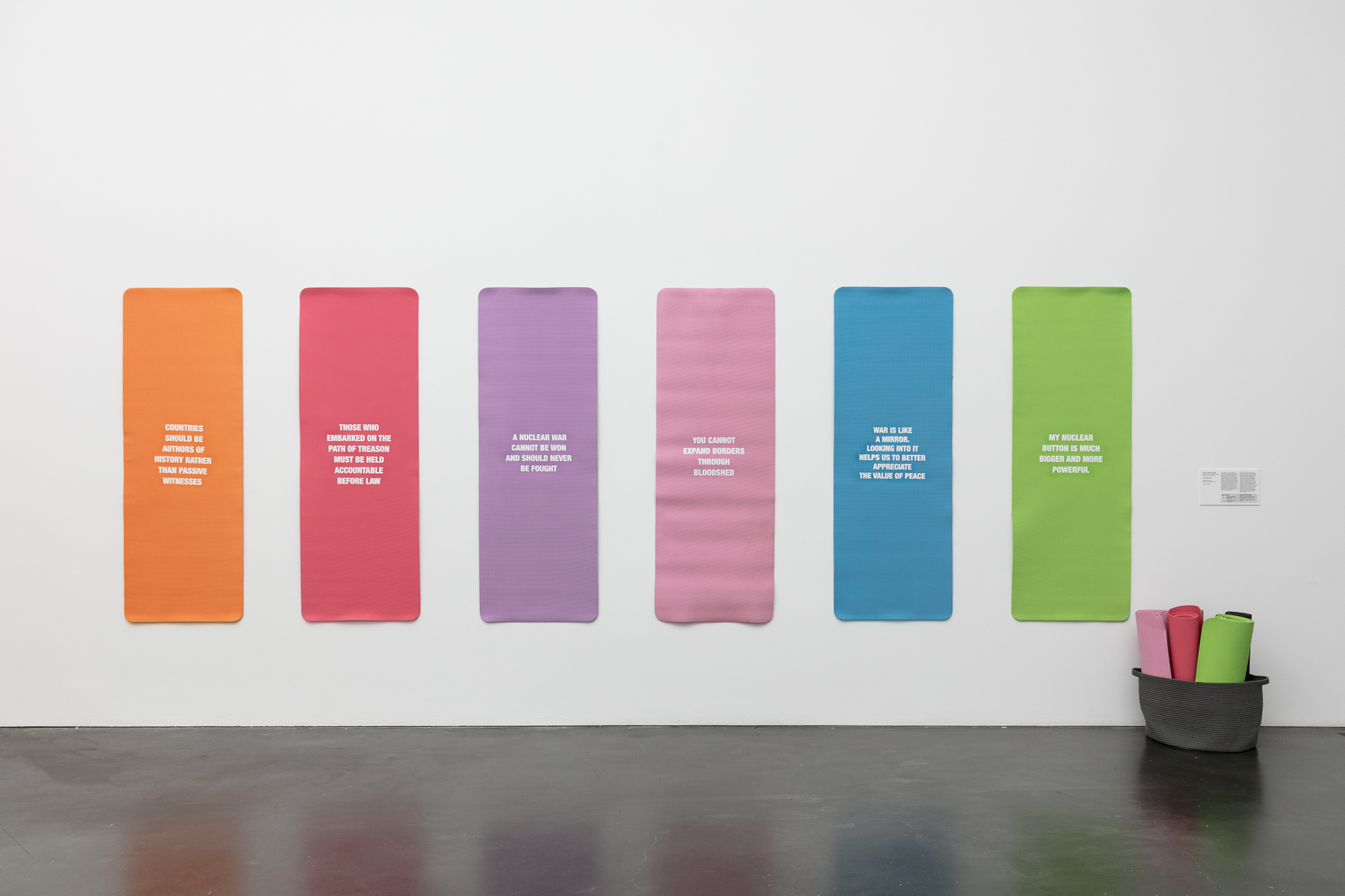 Colorful yoga mats hung on the wall with white text on them.