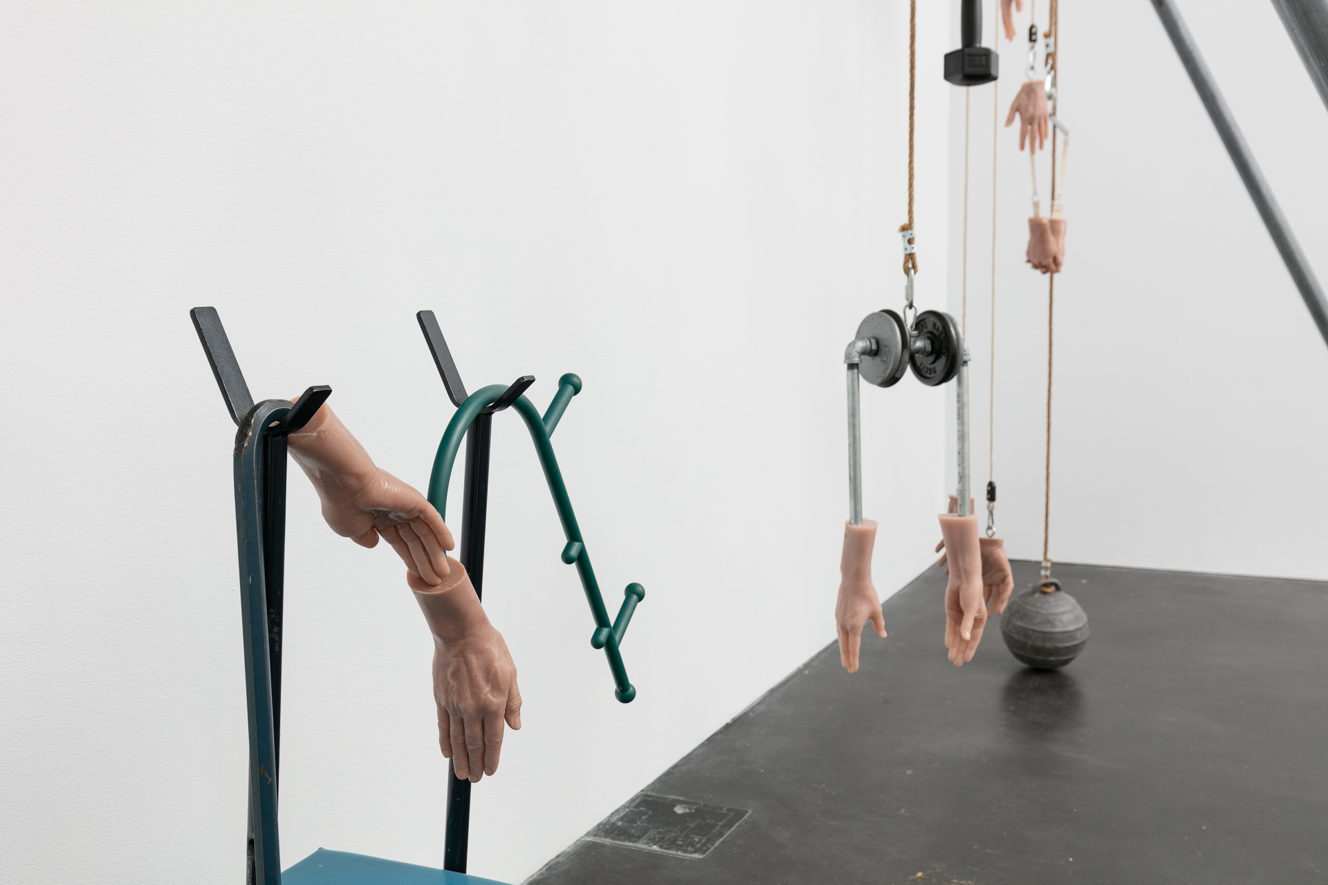 Sculpture that features gym equipment but also cast silicone hands.