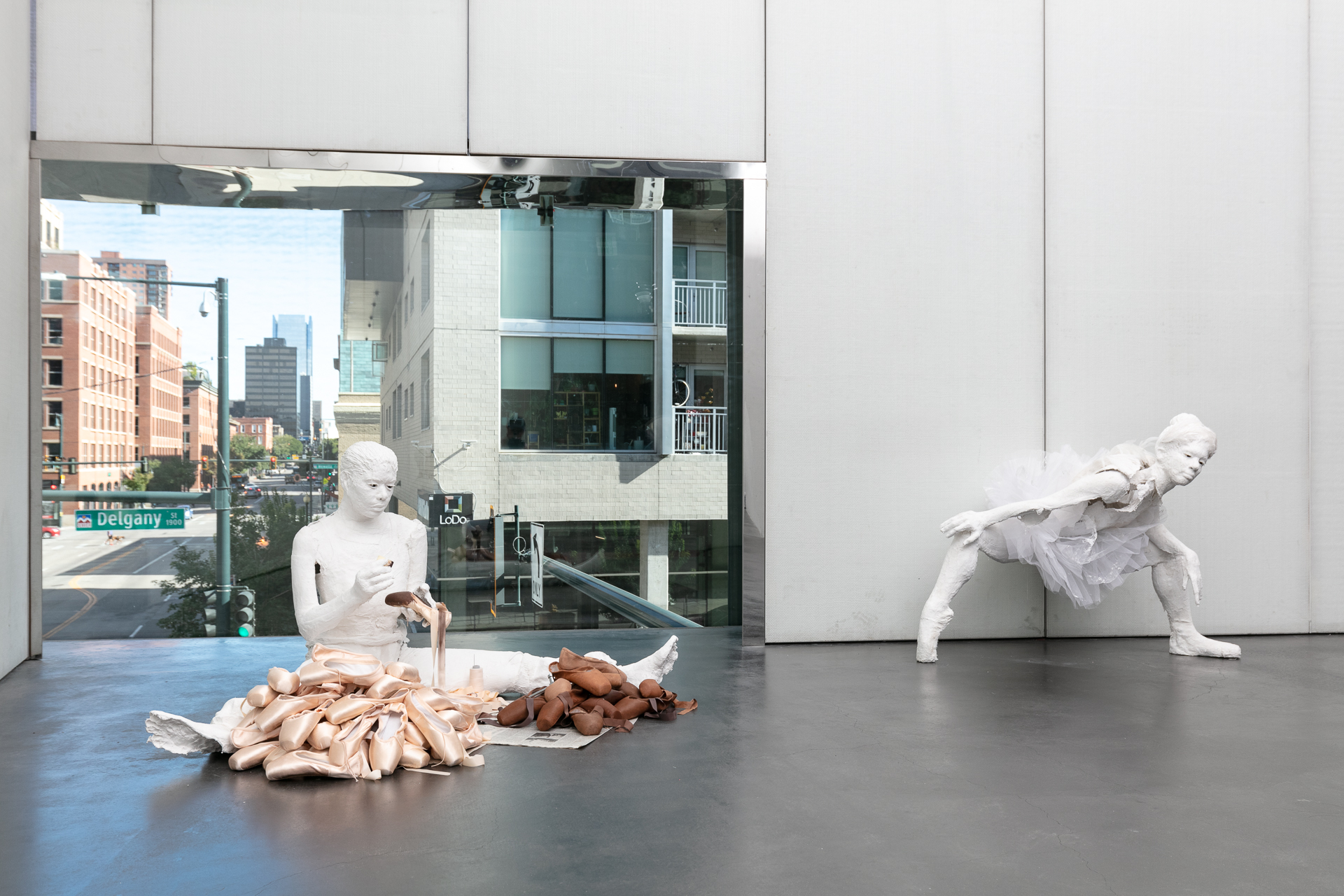 Two white plaster sculptures depicting dancers.