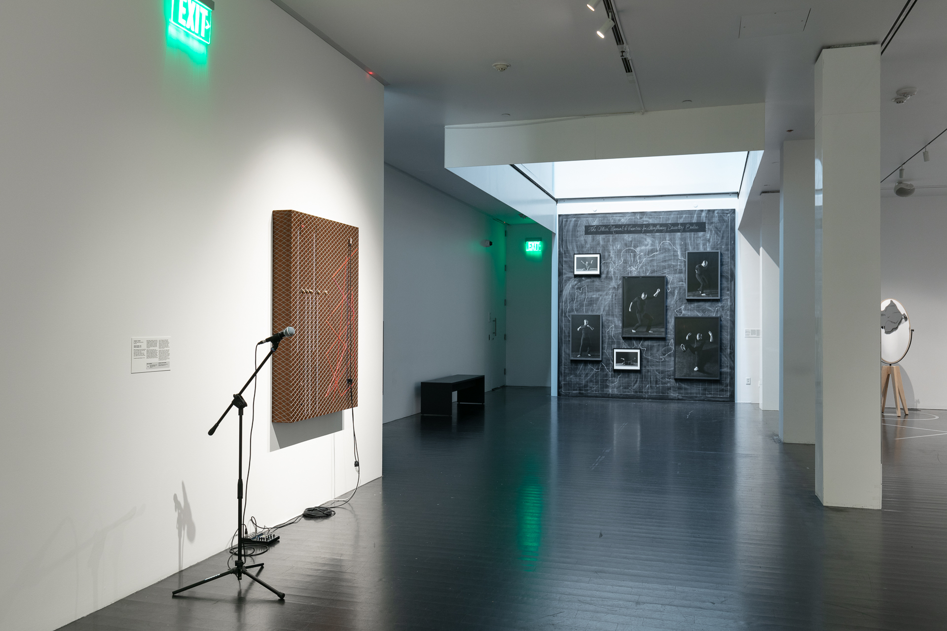 Gallery featuring black and white photos on the wall and an interactive artwork with a microphone hooked up to a deconstructed amp hung on the wall.