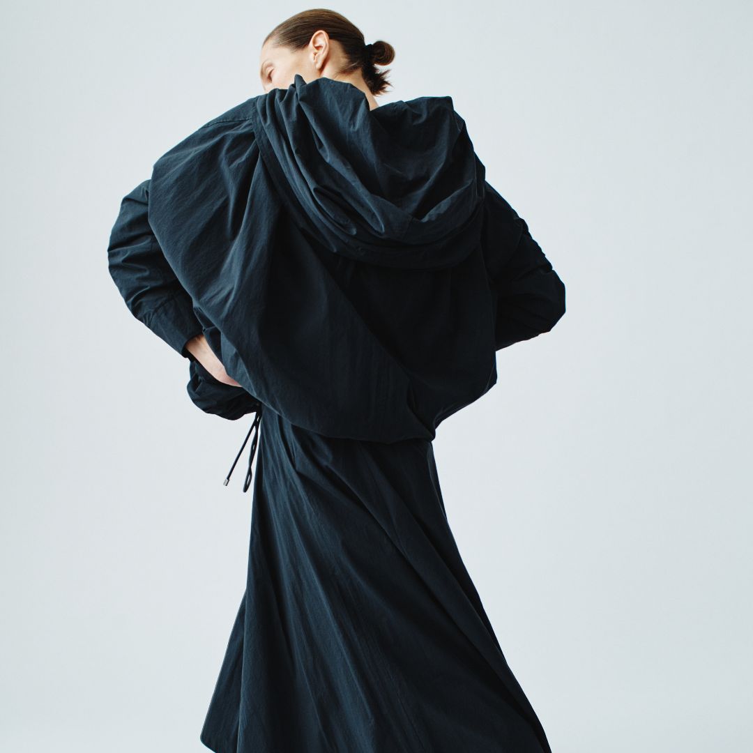 Model with their back towards the camera, sporting an all black outfit.