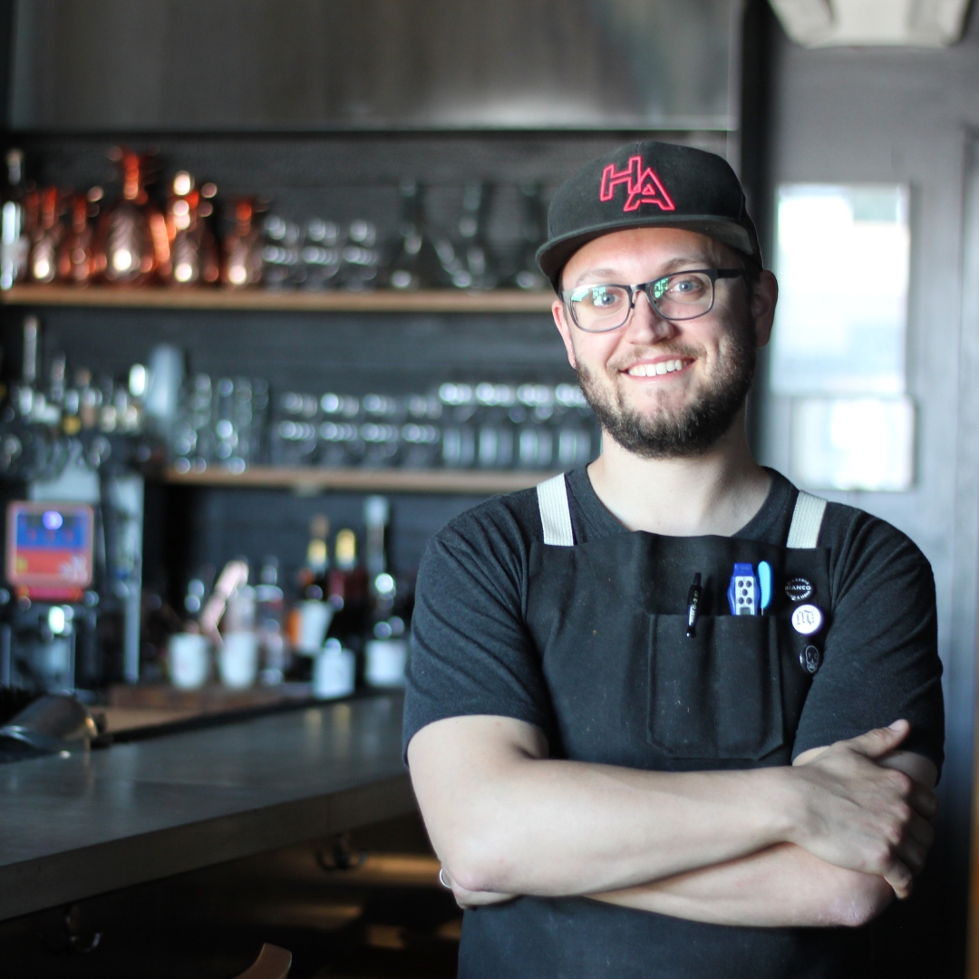 Geoff Cox with his arms crossed and smiling in a restaurant.