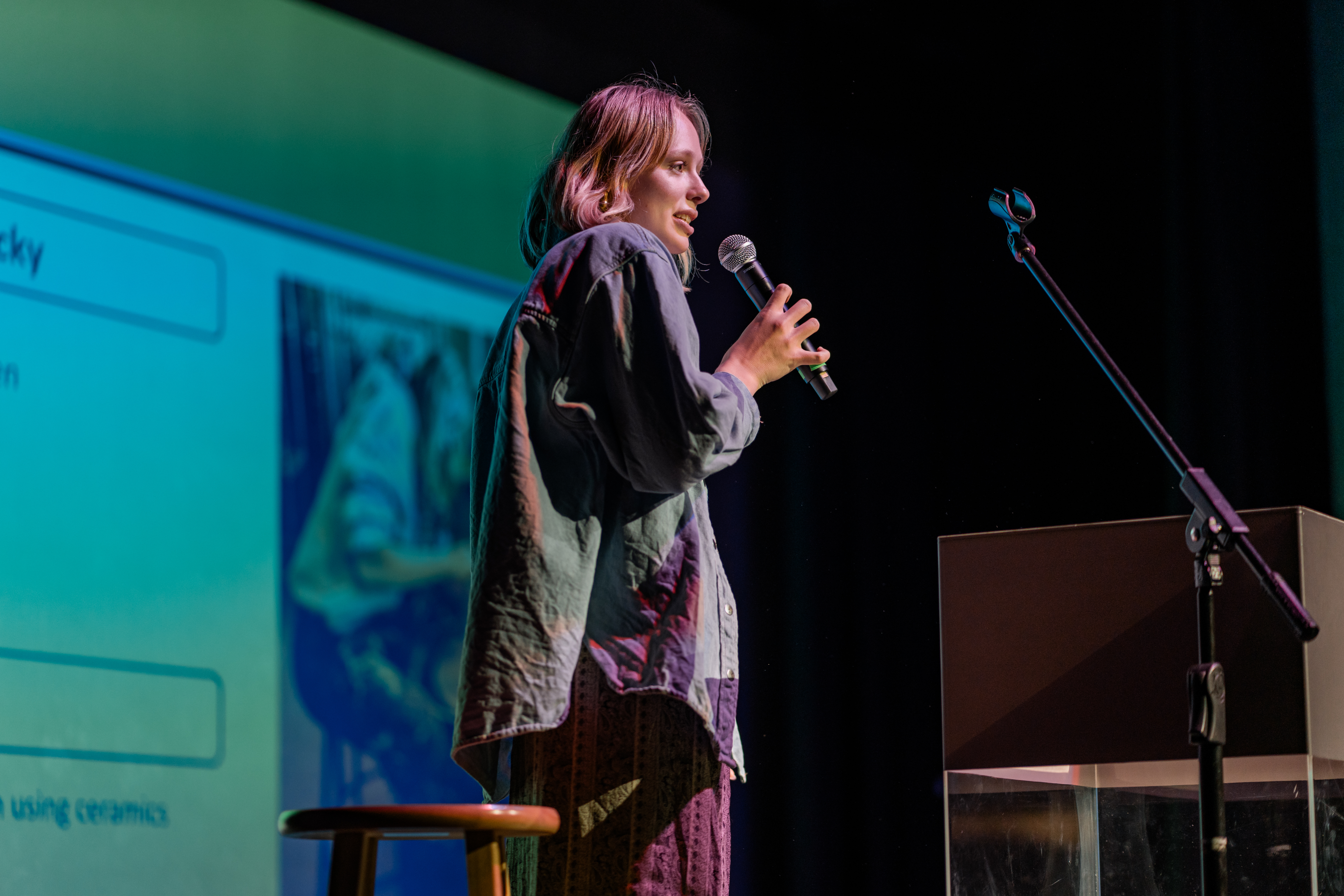 High school senior Josie Wilson speaking into a microphone on a theater stage.