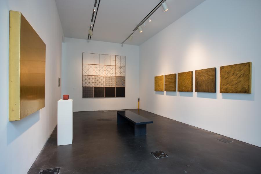 Shot of a gallery with golden colored artworks on the wall. 