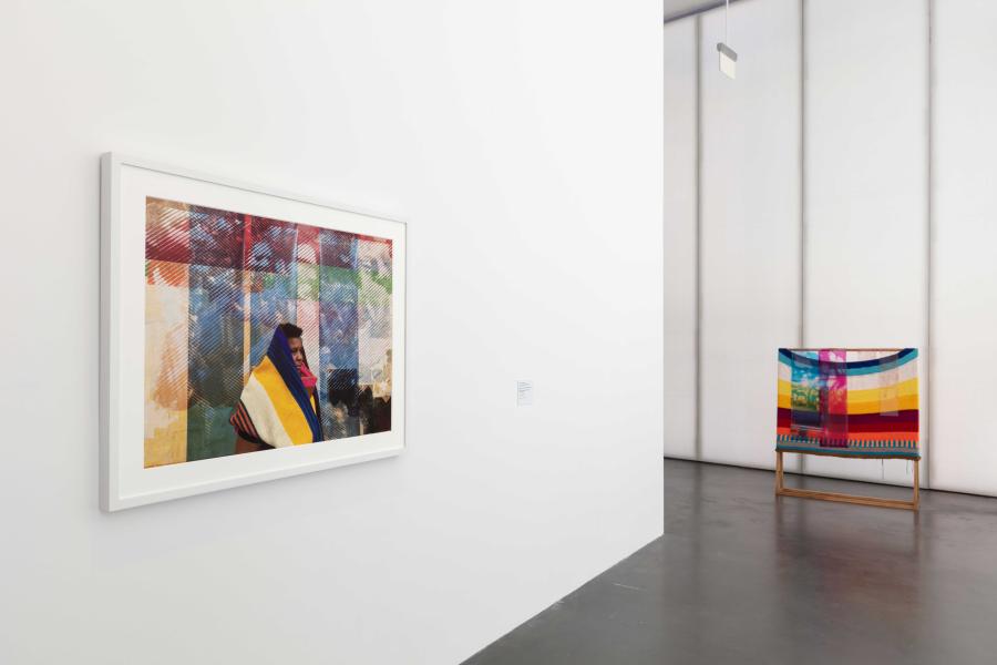 An MCA Denver gallery with artwork framed and hung on a white wall and artwork displayed on the ground in a corner.