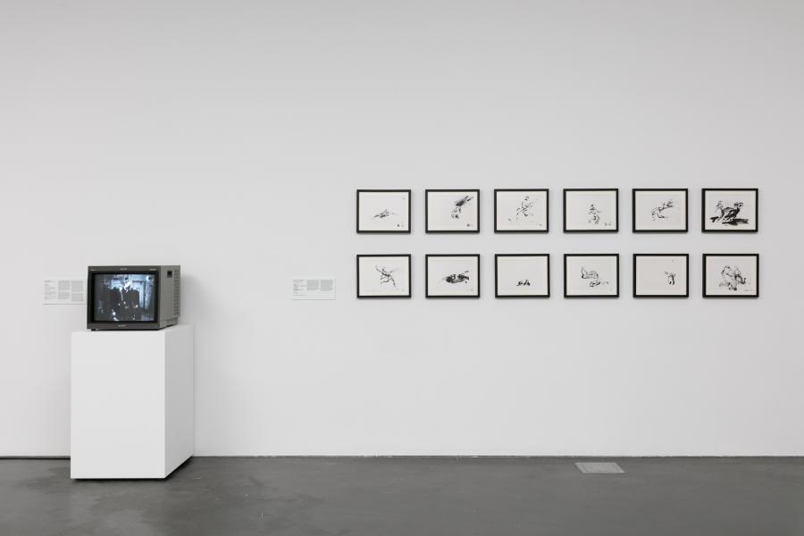 Gallery featuring a small boxy television and a series of small drawings framed and hung on the wall. 