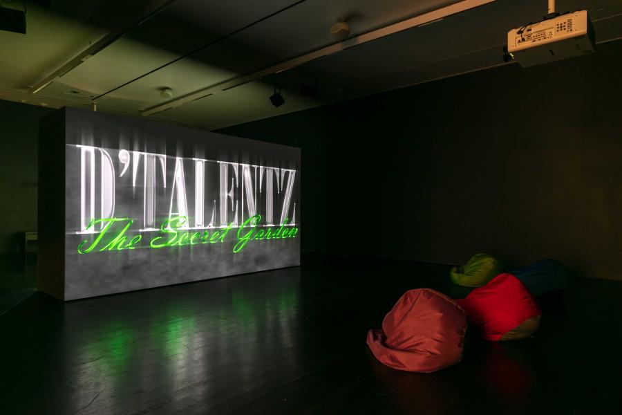 Video projected onto a wall in a dimly lit room. There are bean bags in front of the video.