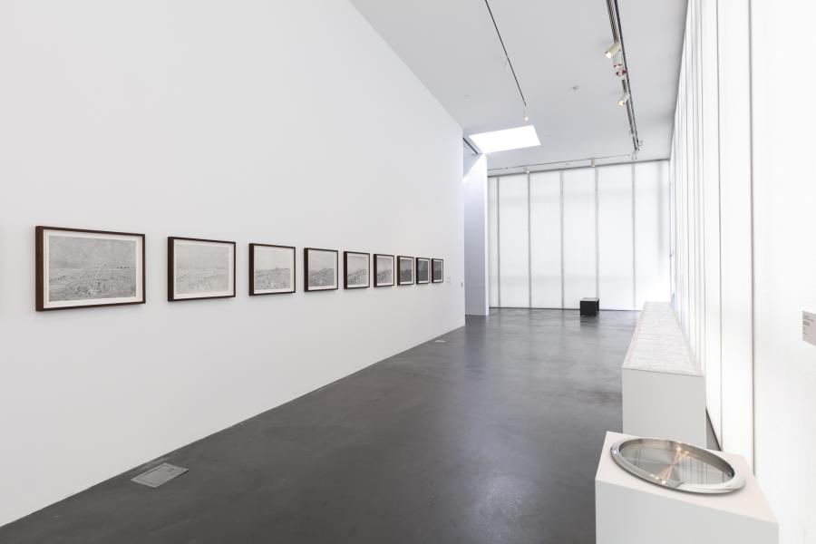Gallery featuring artwork framed and hung on a white wall and artwork displayed on a large white ledge.