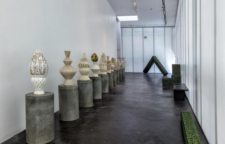 Gallery shot of ceramic artworks. The artworks are cylindrical shapes and made up of modular leaf shapes