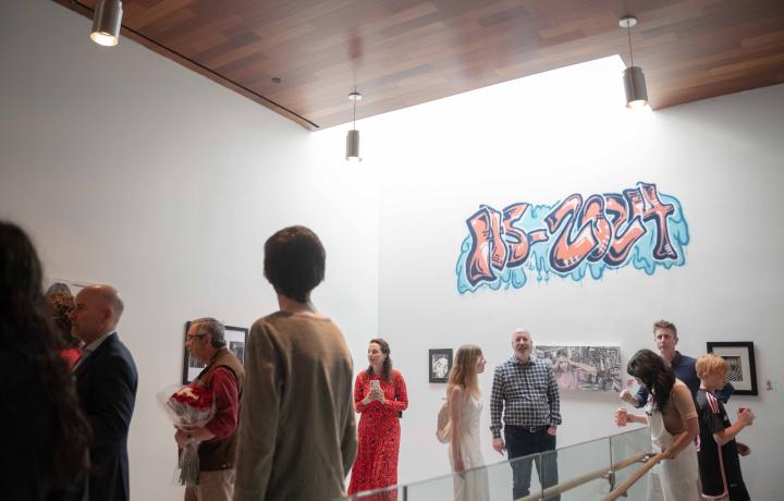 Crowded gallery space with graffiti that reads, "HS '24"