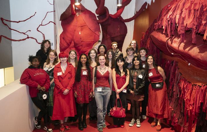 Group of people wearing red standing in a gallery featuring a red installation.