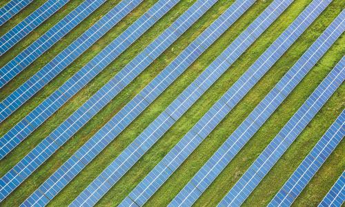A birds-eye view of a solar farm in a green space.